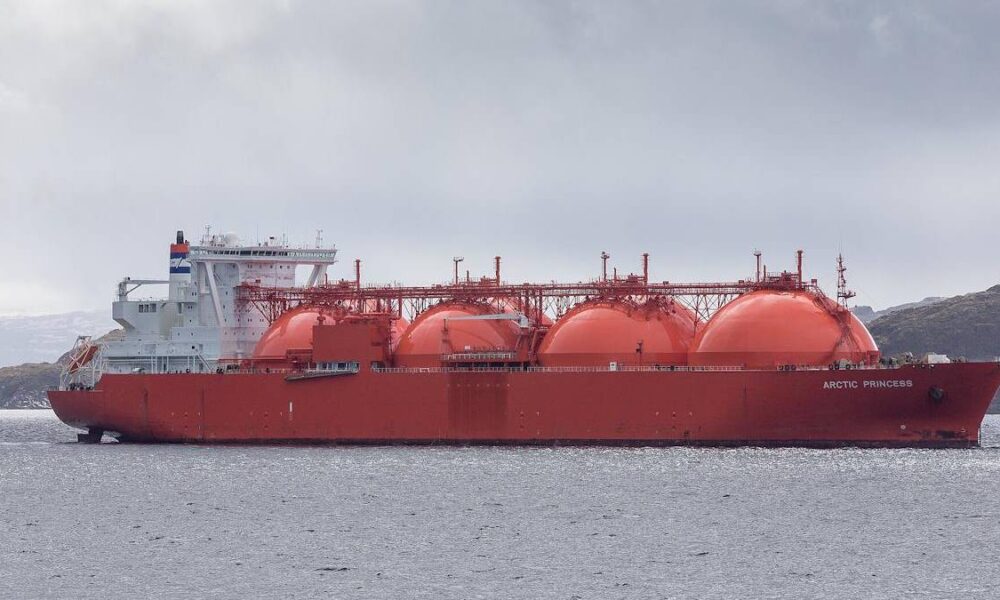 Red LNG carrier Arctic Princess sailing in calm waters with large spherical tanks and a white superstructure on the stern edge of the hull.