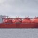 Red LNG carrier Arctic Princess sailing in calm waters with large spherical tanks and a white superstructure on the stern edge of the hull.