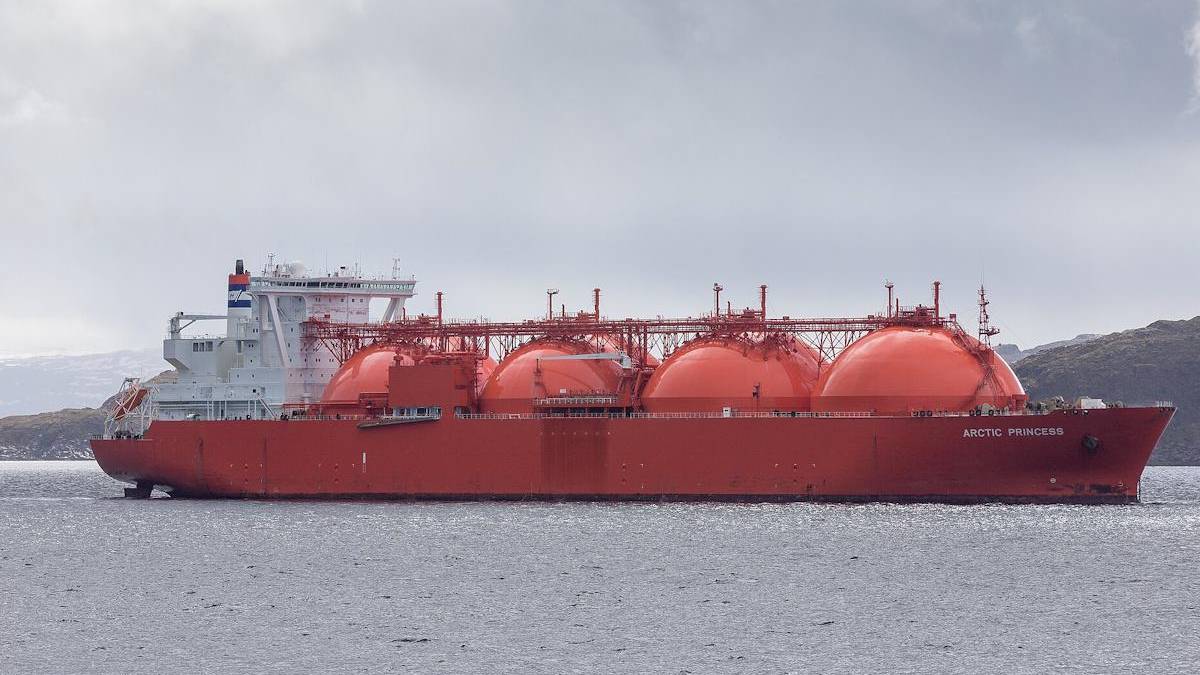 Red LNG carrier Arctic Princess sailing in calm waters with large spherical tanks and a white superstructure on the stern edge of the hull.