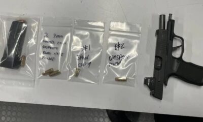 Semi-automatic handgun with a spare magazine on a table, next to three small resealable bags containing bullets and handwritten notes on each bag (evidence layout).