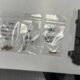 Semi-automatic handgun with a spare magazine on a table, next to three small resealable bags containing bullets and handwritten notes on each bag (evidence layout).