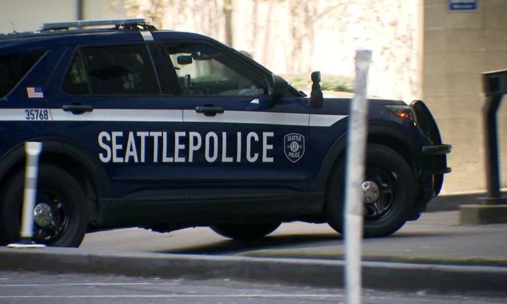 Seattle Police Department SUV with 'SEATTLEPOLICE' lettering parked on a city street, badge visible on the side.