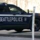 Seattle Police Department SUV with 'SEATTLEPOLICE' lettering parked on a city street, badge visible on the side.
