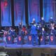 Shorewood High School Jazz Band performs on stage with a conductor directing the players and banners in blue backdrop.