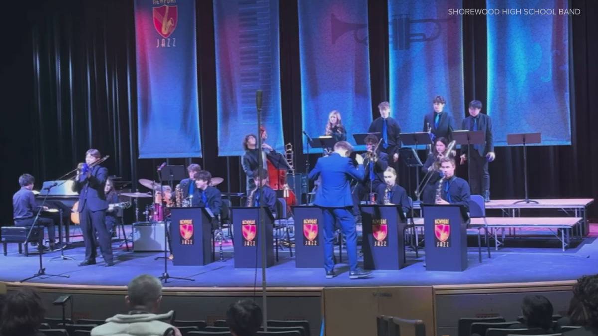 Shorewood High School Jazz Band performs on stage with a conductor directing the players and banners in blue backdrop.