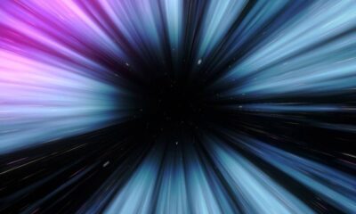 Abstract warp-speed tunnel with colorful light streaks converging into a black vanishing point, conveying deep space motion.
