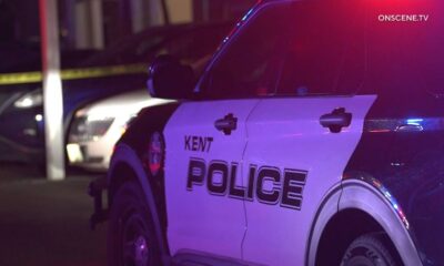 Kent Police SUV at night with red and blue emergency lights flashing; police tape in the background.