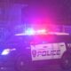 Tacoma Police Department SUV with red and blue emergency lights flashing at night beside a chain-link fence.