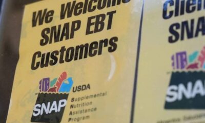Sign reads 'We Welcome SNAP EBT Customers' with a small USDA SNAP logo on a yellow background (close-up).