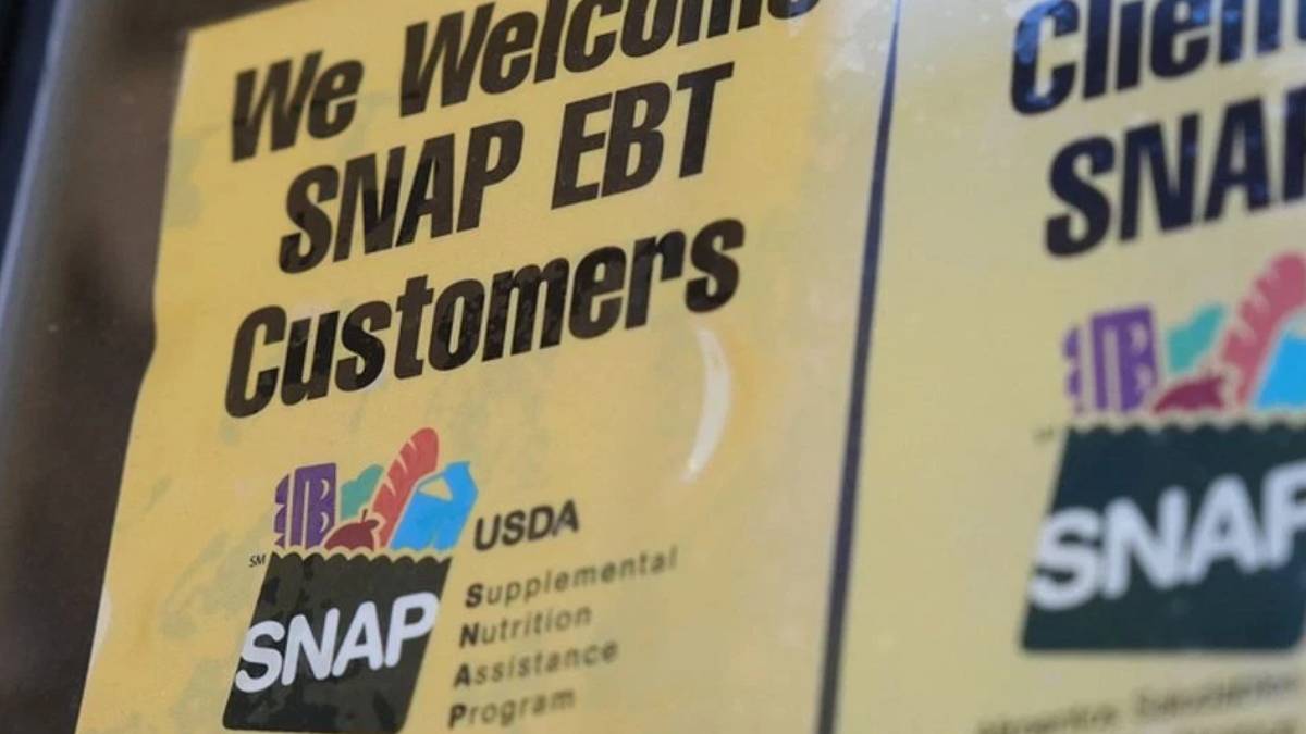 Sign reads 'We Welcome SNAP EBT Customers' with a small USDA SNAP logo on a yellow background (close-up).
