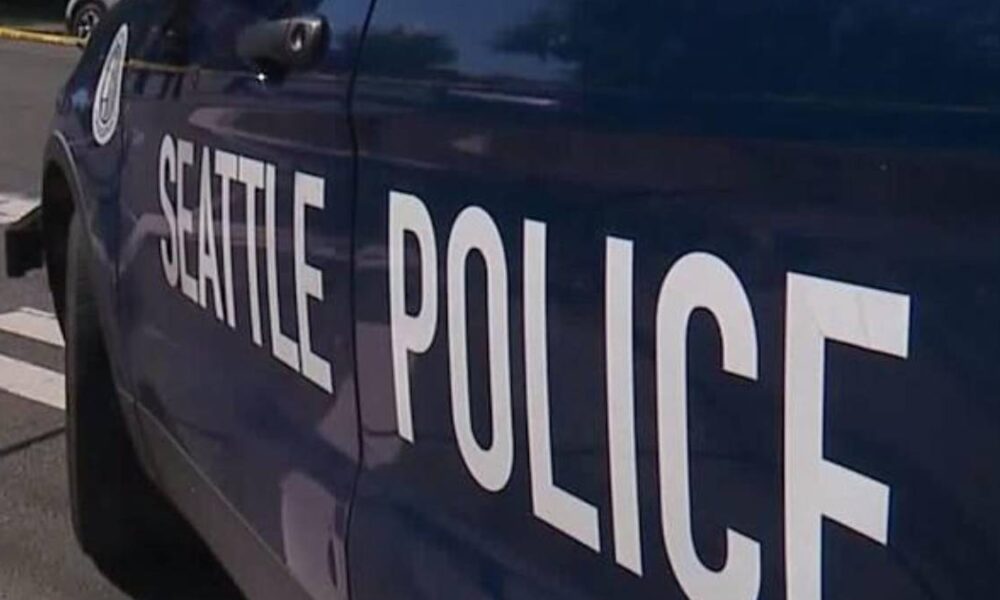 Side view of a dark blue Seattle Police vehicle with large white 'SEATTLE POLICE' lettering on the door.