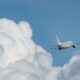Commercial airliner flying through a blue sky with large white clouds nearby.