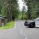 Sheriff SUV blocking a quiet residential road with a 'Road Closed' sign in the foreground and trees lining the street.