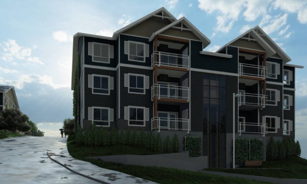 Modern four-story apartment building with balconies on a sloped lawn under a blue sky.