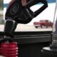 Close-up of a fuel nozzle being inserted into a car's fuel tank at a gas station.