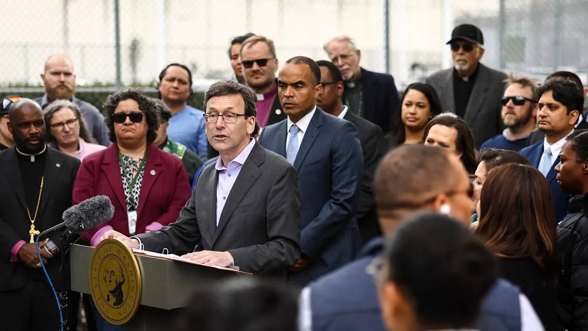 Politician at a podium giving a press conference, surrounded by a diverse crowd of onlookers and reporters.