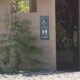 Exterior restroom building with multiple wheelchair-accessible signs on the walls and graffiti visible inside the doorway.