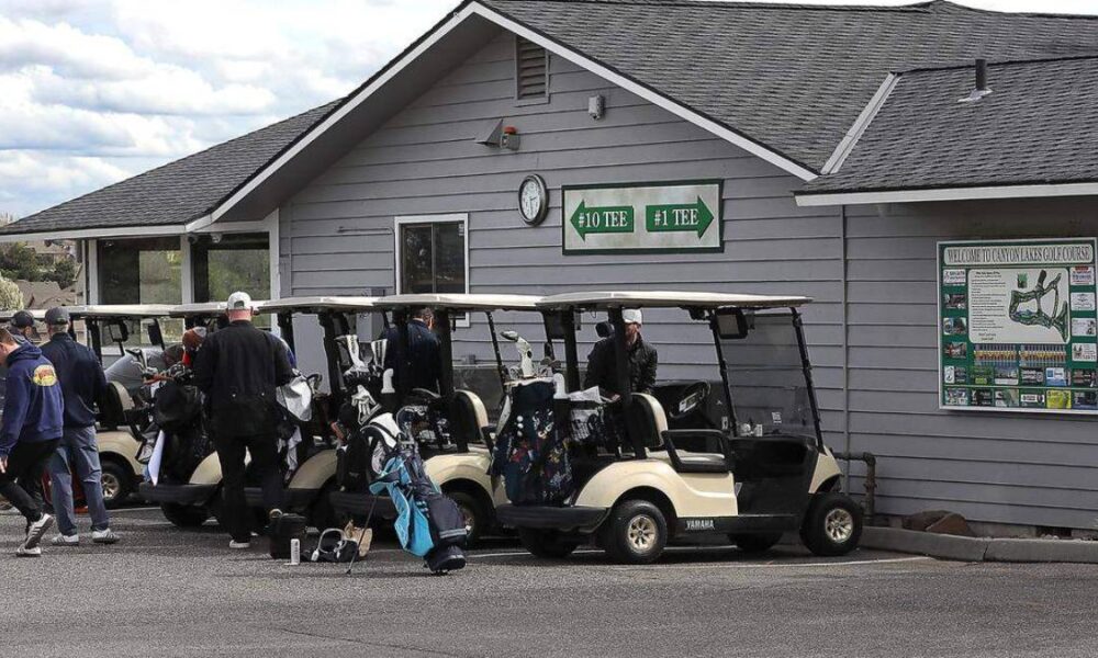 Golf carts lined up outside a golf club with players and bags ready to play. Sign shows #10 and #1 tees on the building.