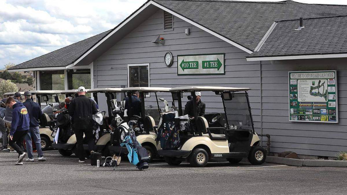 Golf carts lined up outside a golf club with players and bags ready to play. Sign shows #10 and #1 tees on the building.