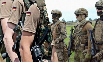 Group of soldiers in combat gear standing in a field, each carrying rifles and wearing camouflage uniforms.