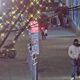 Sidewalk scene with decorative string lights, a large DO NOT ENTER sign on the left, and several people near a muraled wall.