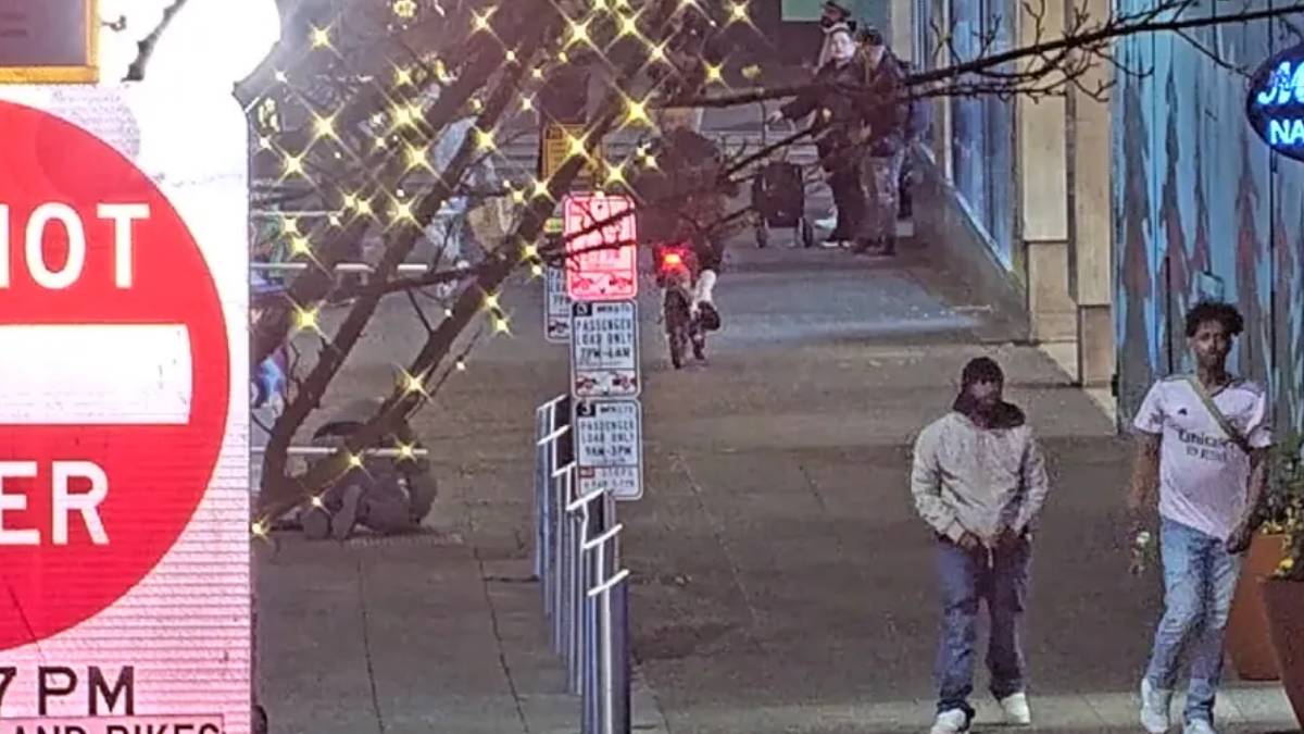 Sidewalk scene with decorative string lights, a large DO NOT ENTER sign on the left, and several people near a muraled wall.