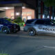 Two police SUVs parked on a city street at night; one shows Seattle Police lettering, the other reads POLICE.