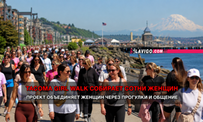 Large group of women walking along a seaside promenade with water and mountains in the background; bold news banner across the center reads Tacoma Girl Walk...