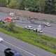 Multiple vehicles involved in a highway crash with emergency responders on a divided freeway median.