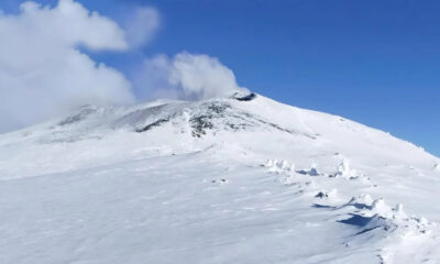 Snow-covered mountain slope under a blue sky with a few clouds.