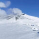 Snow-covered mountain slope under a blue sky with a few clouds.
