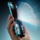 Hand holding a teal smartphone with a glowing brain hologram projecting from the screen, symbolizing AI technology