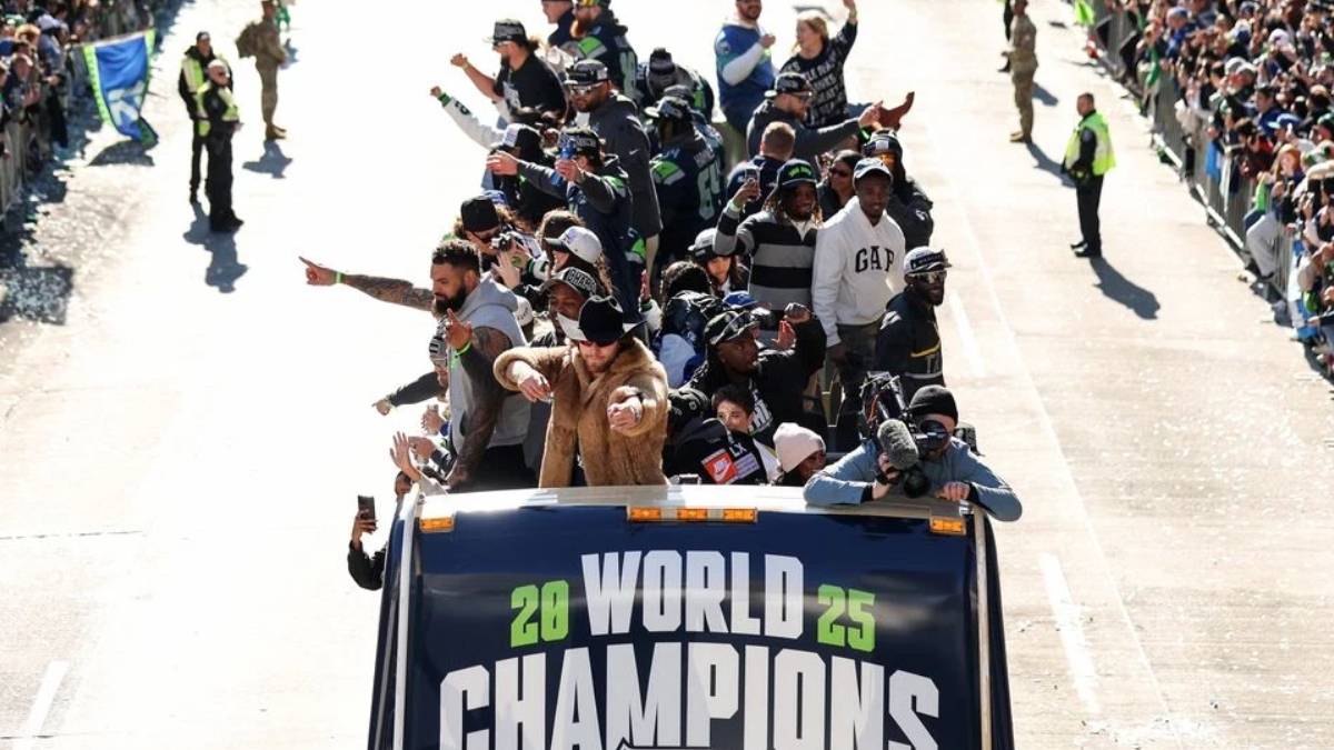 Group of athletes standing and waving from an open-top vehicle during a street parade, banner reads WORLD CHAMPIONS 2025.