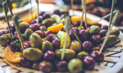 Plate of mixed olives on skewers with lemon wedges, a tapas-style appetizer area.