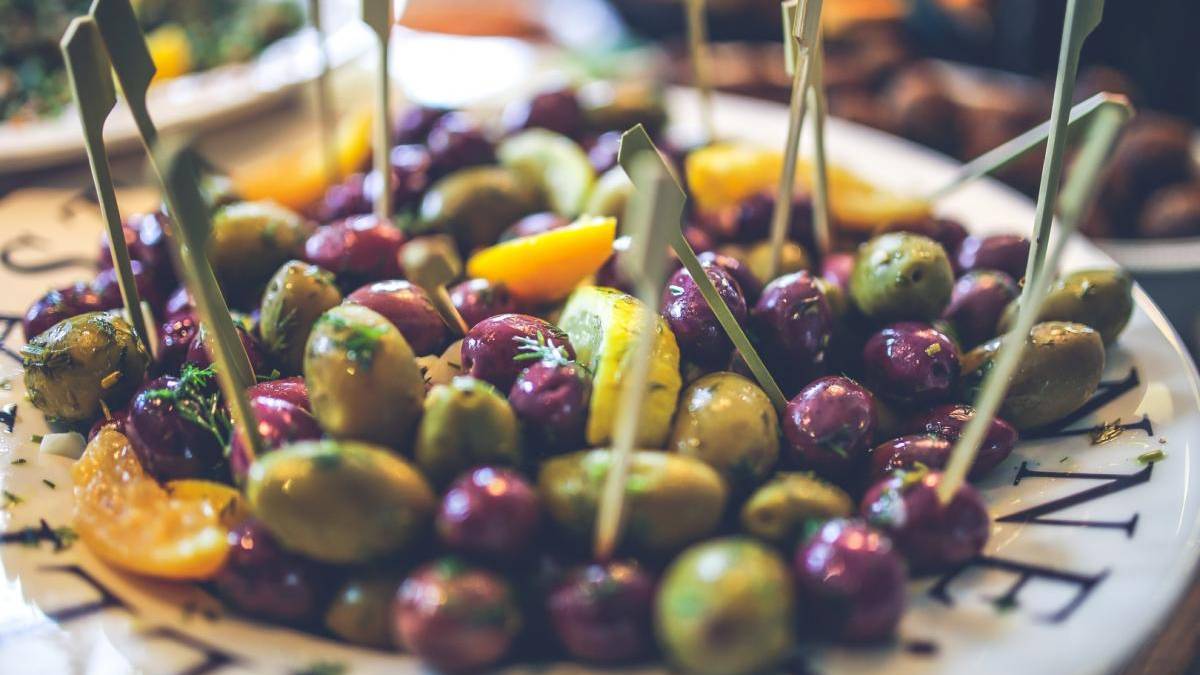 Plate of mixed olives on skewers with lemon wedges, a tapas-style appetizer area.