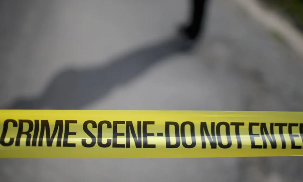 Yellow crime scene tape reading 'CRIME SCENE- DO NOT ENTER' stretched across a blurred outdoor area, signaling a restricted area.