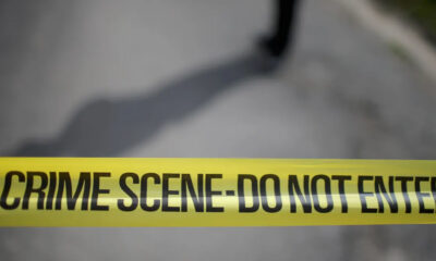 Yellow crime scene tape reading 'CRIME SCENE- DO NOT ENTER' stretched across a blurred outdoor area, signaling a restricted area.