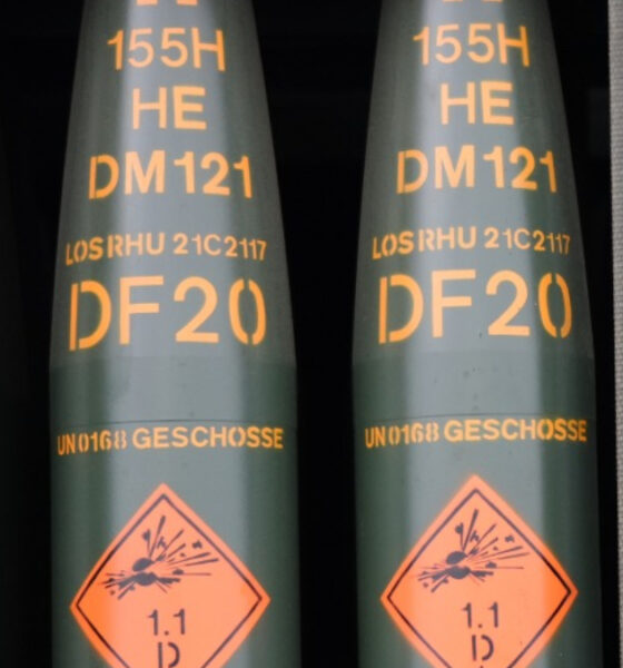 Row of green cylindrical ordnance with orange DF20 markings and a diamond warning label showing explosive hazard (1.1).