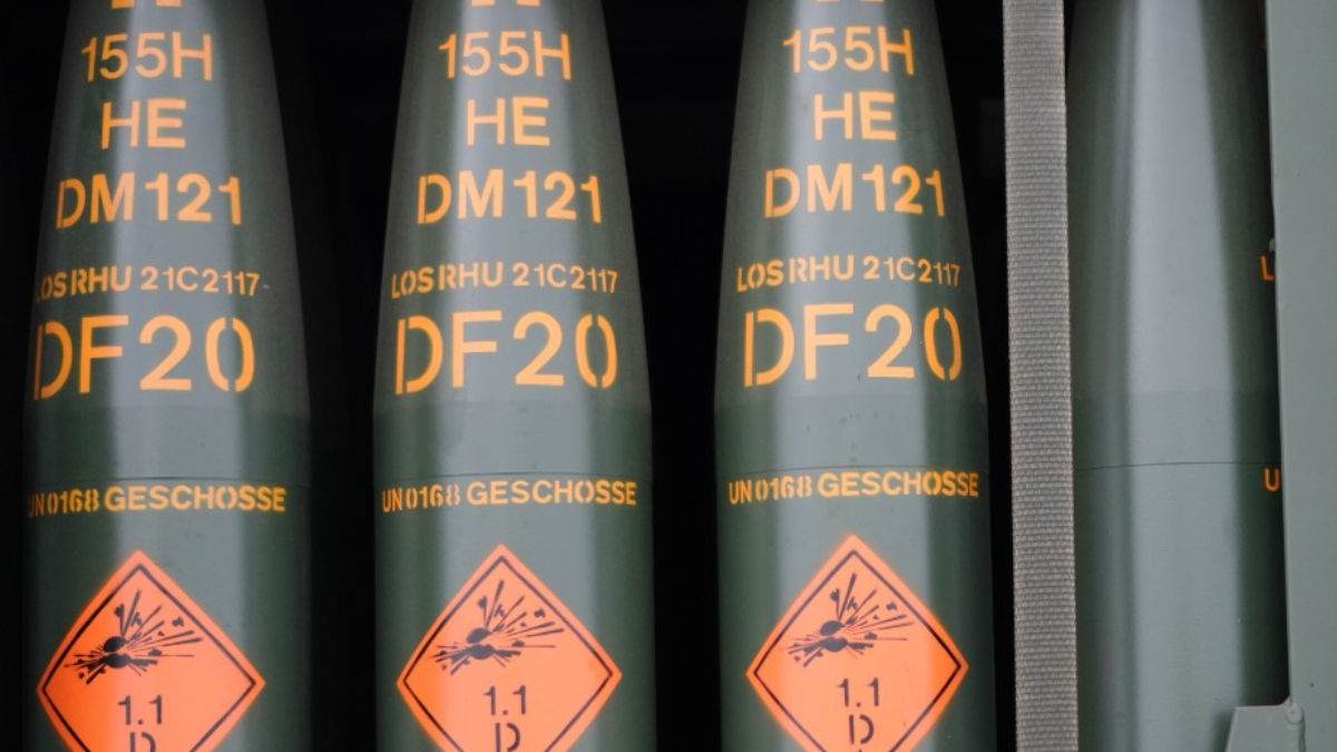 Row of green cylindrical ordnance with orange DF20 markings and a diamond warning label showing explosive hazard (1.1).