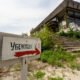 Abandoned building with overgrown vegetation and a weathered sign in Russian pointing right toward shelter 1.