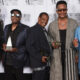 Five men pose on a red carpet backdrop reading Songwriters Hall of Fame, each holding a trophy award.