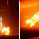 Rocket on a launch pad erupts in a bright flame and smoke at night that lights the area left of center it