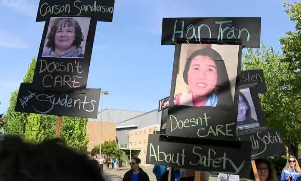 Protesters hold black signs with chalky white text and portrait photos; messages say 'Doesn't CARE About Students' and similar statements.