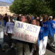 Group of students marching outside, holding a sign that reads "Our Safety > Your Politics" during a campus demonstration.