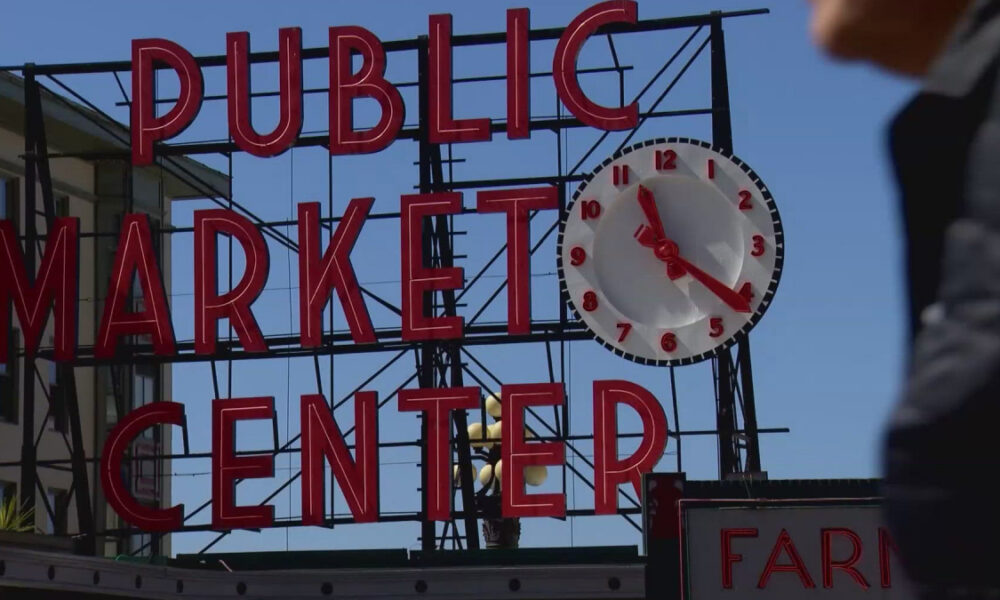 Sign reads 'Public Market Center' with a large round clock mounted on the right side of the sign.