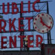 Sign reads 'Public Market Center' with a large round clock mounted on the right side of the sign.