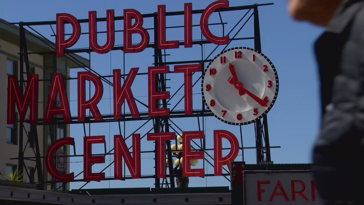 Sign reads 'Public Market Center' with a large round clock mounted on the right side of the sign.