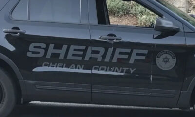 Black sheriff SUV side with large 'SHERIFF CHELAN COUNTY' lettering and a circular sheriff badge on the front door