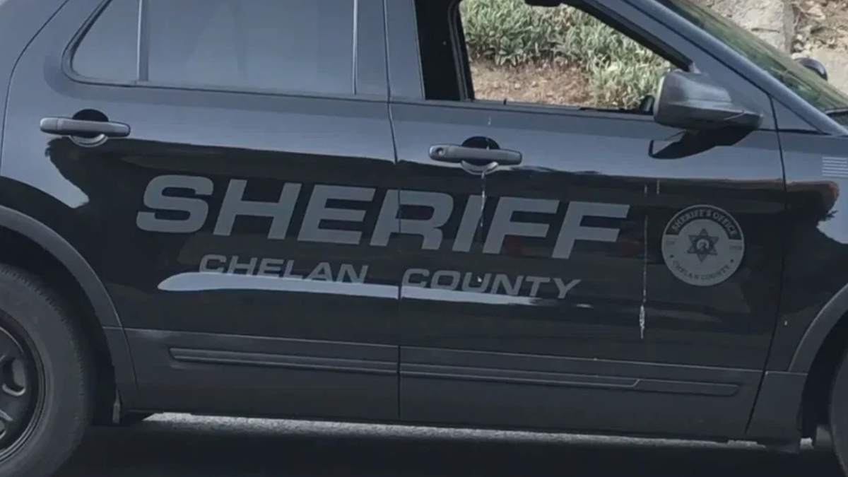 Black sheriff SUV side with large 'SHERIFF CHELAN COUNTY' lettering and a circular sheriff badge on the front door