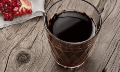 Glass of red wine on a weathered wooden table with pomegranate seeds on a white napkin in the corner on the left.